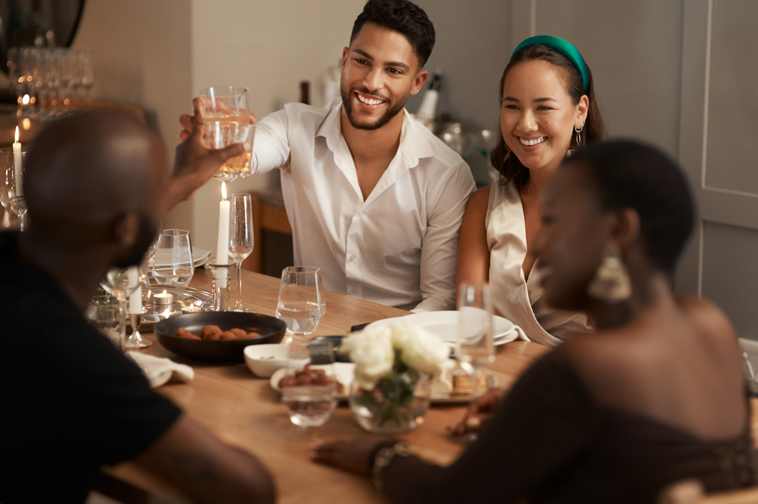Group of friends at dinner party, diverse couples drink and eat happy