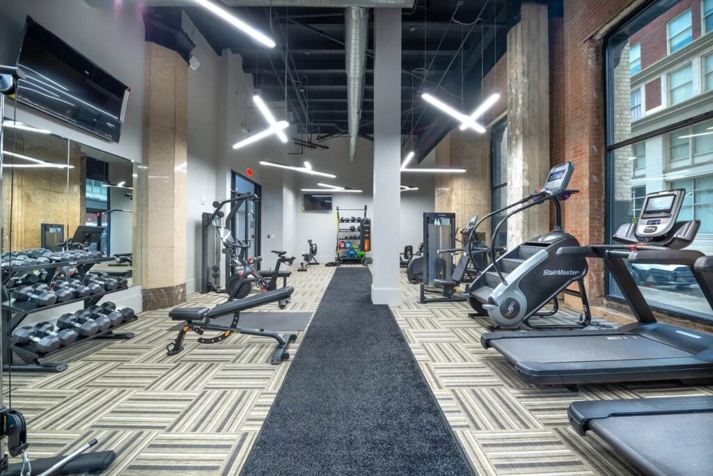 Large fitness center with weights, TVs, a boxing bag and cardio and strength machines including stairs and treadmills