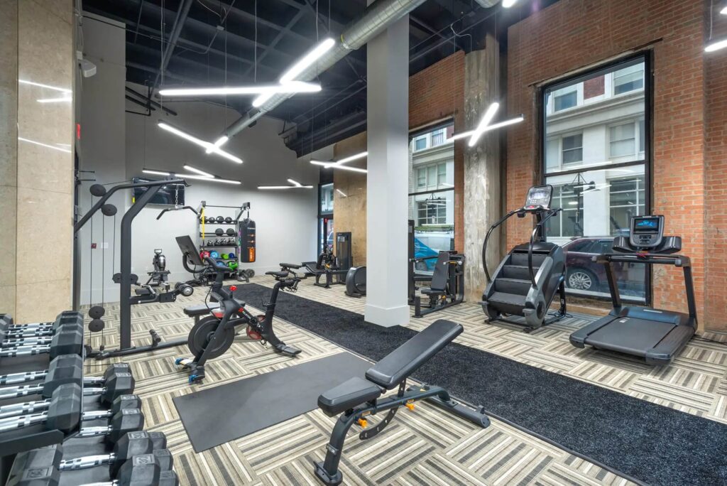 Large fitness center with weights, TVs, a boxing bag and cardio and strength machines including stairs, cycles and treadmills