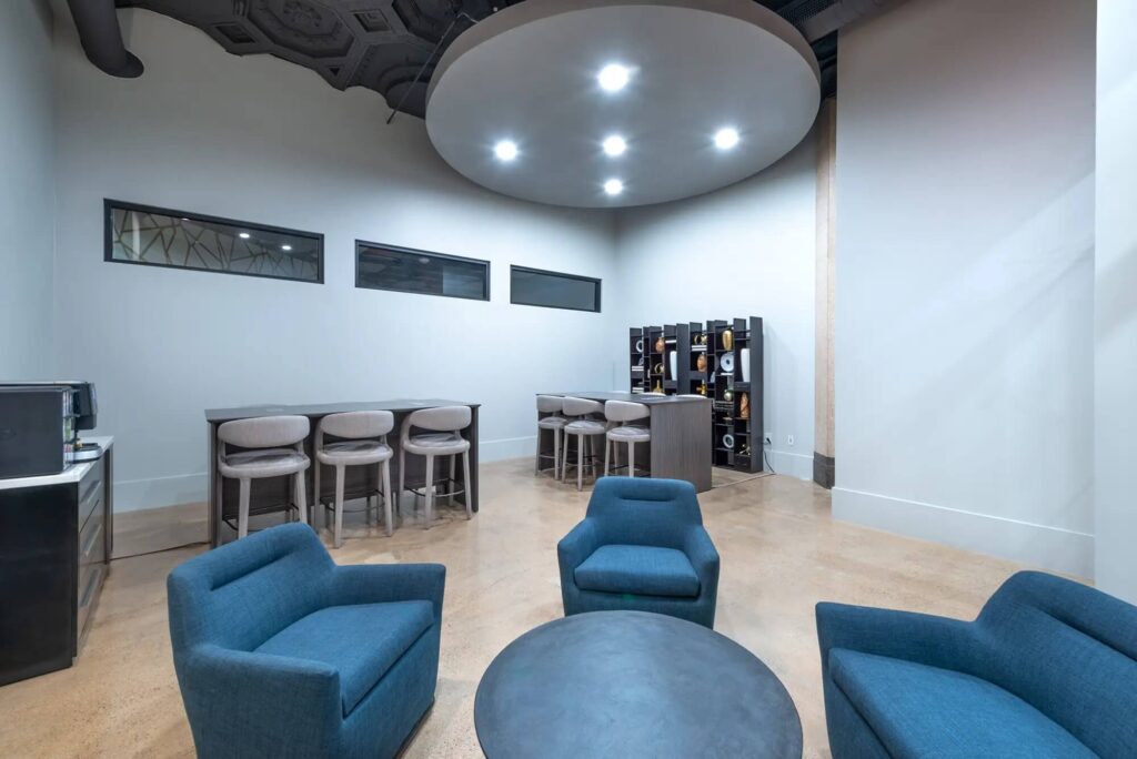 Clubhouse area with coffee machine, many stools at tables and plush seating