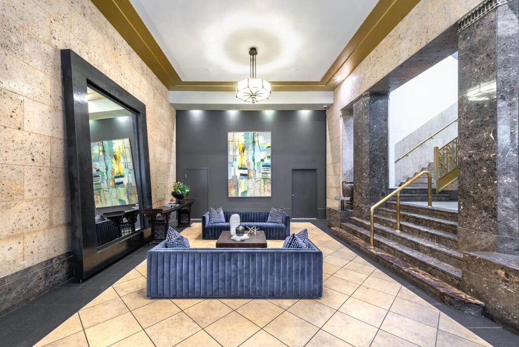 Hallway with grand stairway, enormous mirror, and two big blue couches