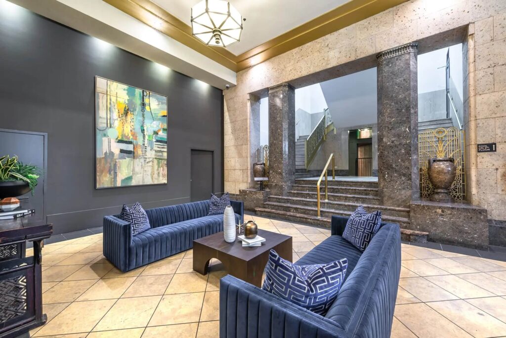 Hallway with grand stairway and two big blue couches