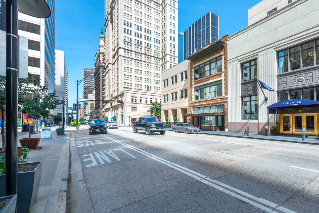 City street in Dallas with vehicles driving past The Joule hotel.