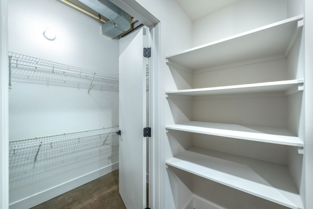 A walk-in closet featuring wire shelving on the left and white wooden shelves on the right.